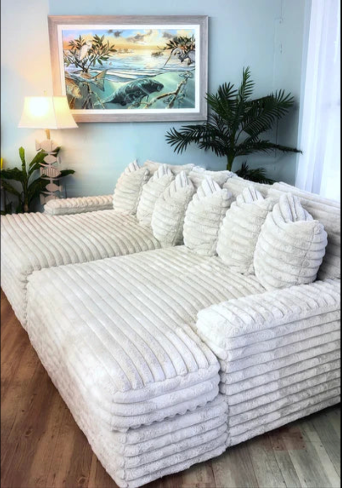 White corduroy textured sofa in a living room with a framed picture and plants.