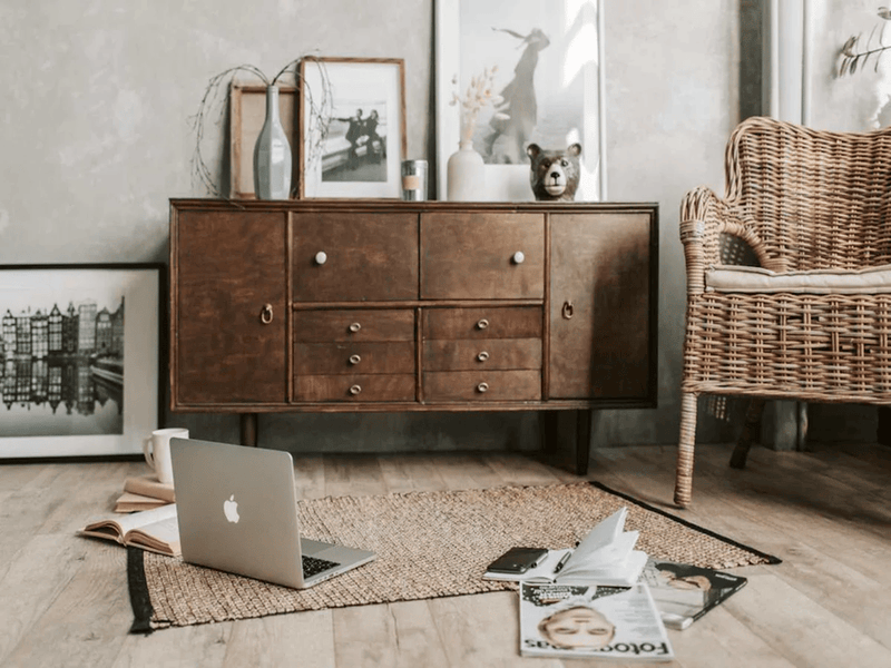 Brown wooden accent cabinet with photo frames on top of it