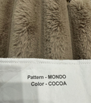 Close-up of a textured fabric with 'Pattern - MONDO' and 'Color - COCOA' text on a white label.